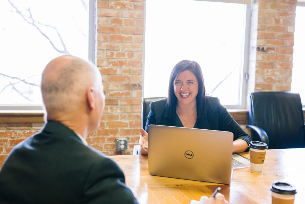 A woman in a suit behind her laptop talking to a client
