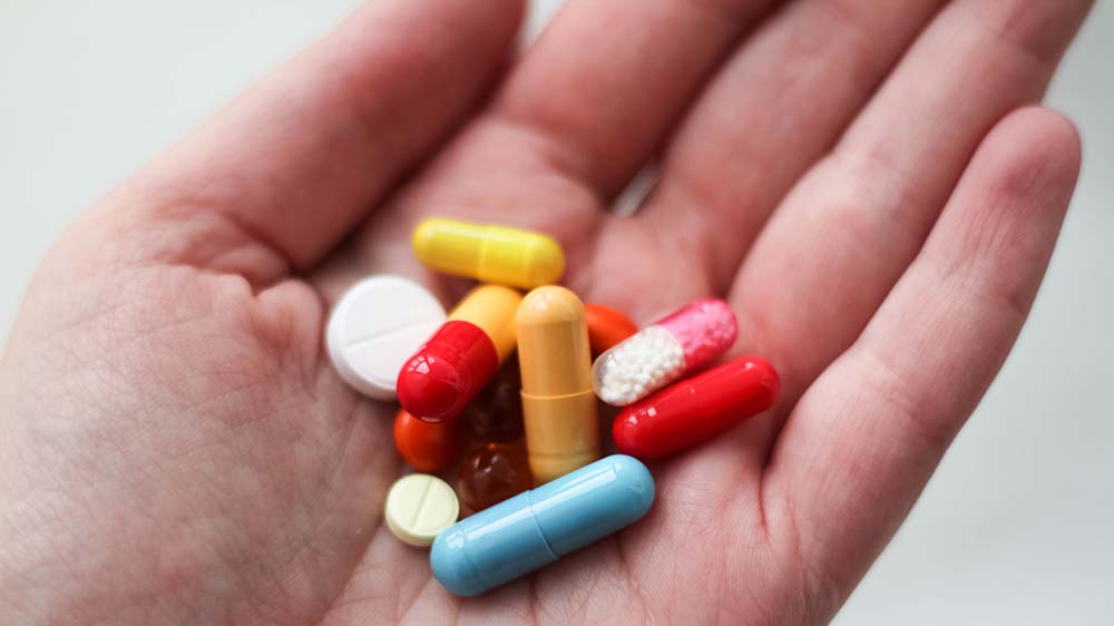 A variety of multi-coloured pills in the palm of a hand